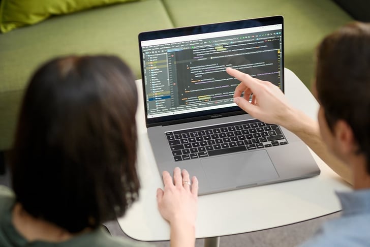 Man showing screen, that depicts codes, to a woman