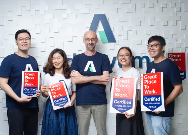Female and male working colleagues behind table at Adnovum Vietnam holding up certification 