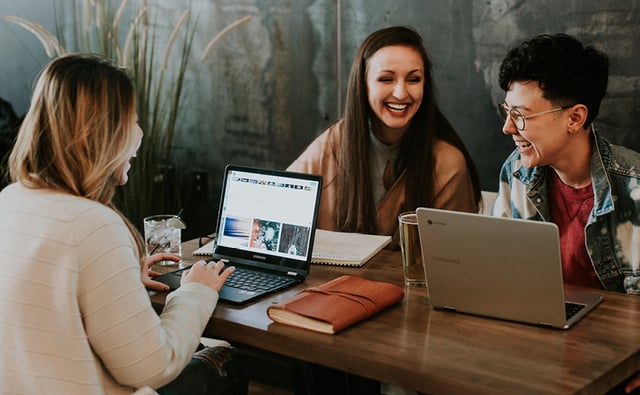 Female and male working colleagues smiling and looking at a laptop screen 