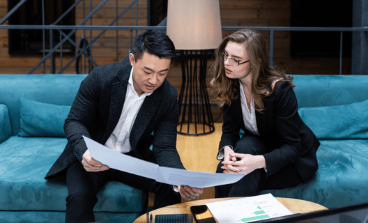 Two business associates seated while having a discussion over some documents.