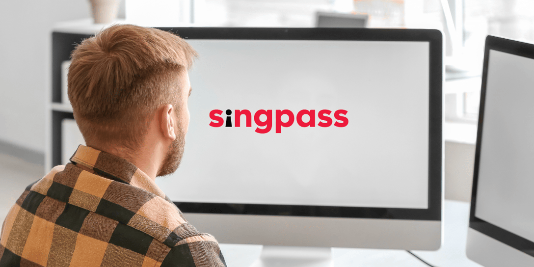 Male user seated in front of a monitor screen showing the Singpass logo