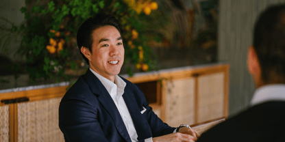An Asian businessman in suit speaking to a counterpart in a meeting.