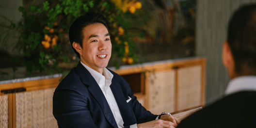 An Asian businessman in suit speaking to a counterpart in a meeting.