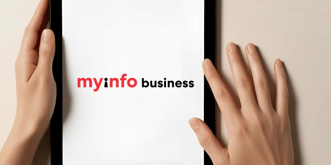 A pair of hands holding a black tablet with the Myinfo business logo in the center of the tablet screen.