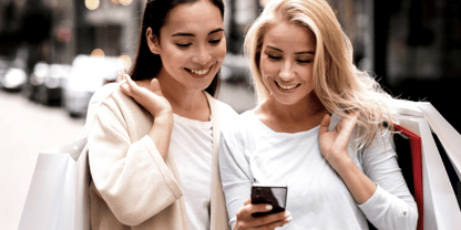 Two shoppers are using a phone to share their information