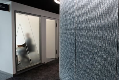 Man in meeting room seen from behind through glass wall 