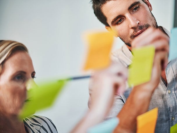 Two colleagues writing notes on post-its