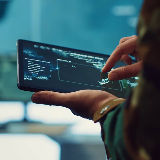 Person holding a tablet and interacting with on-screen data.