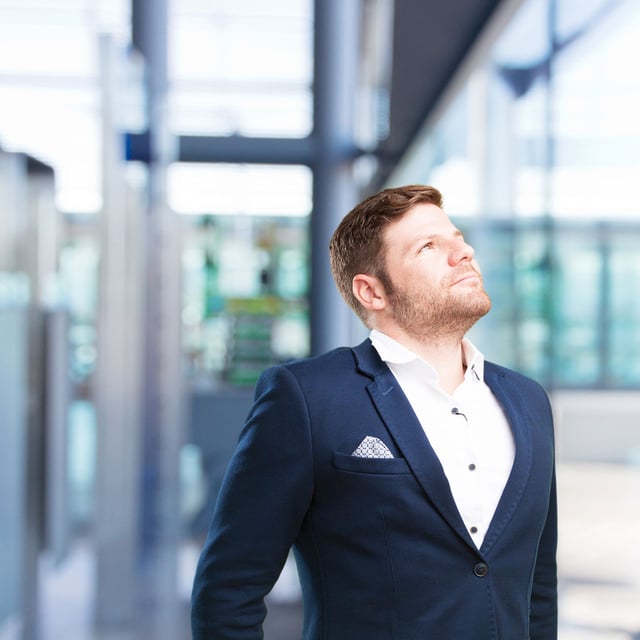 A man in a suit taking a deep breath and looking at the sky